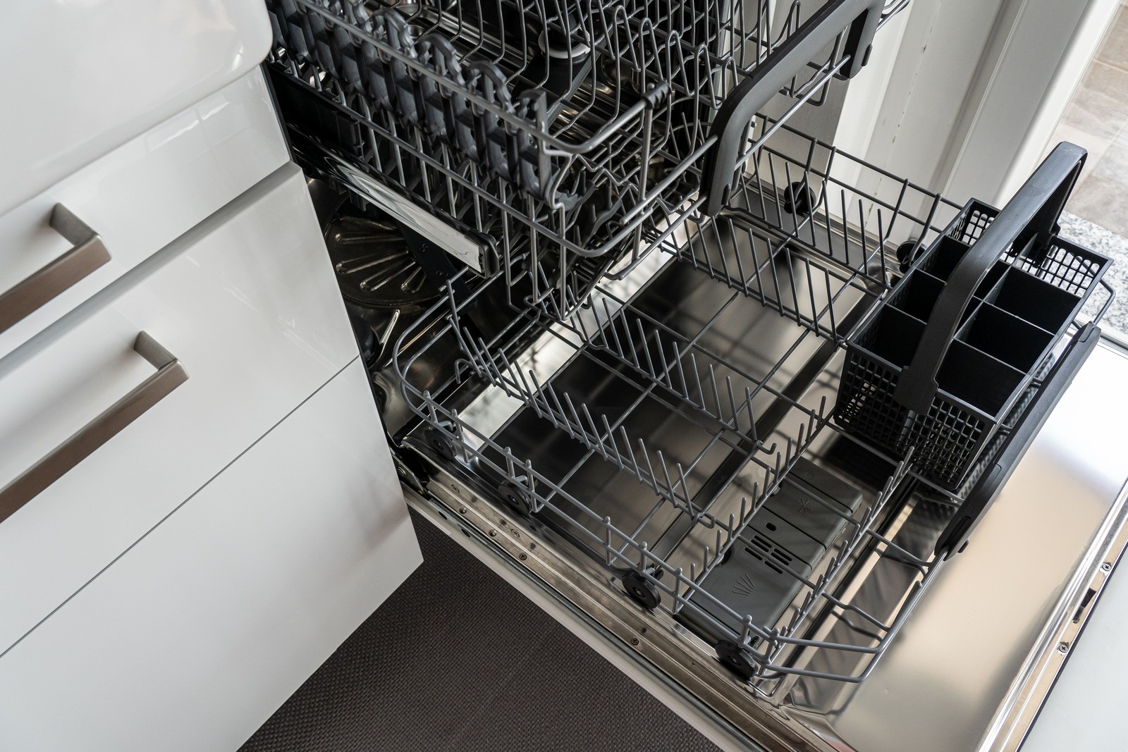 Open dishwasher door showing the dish racks and filter area