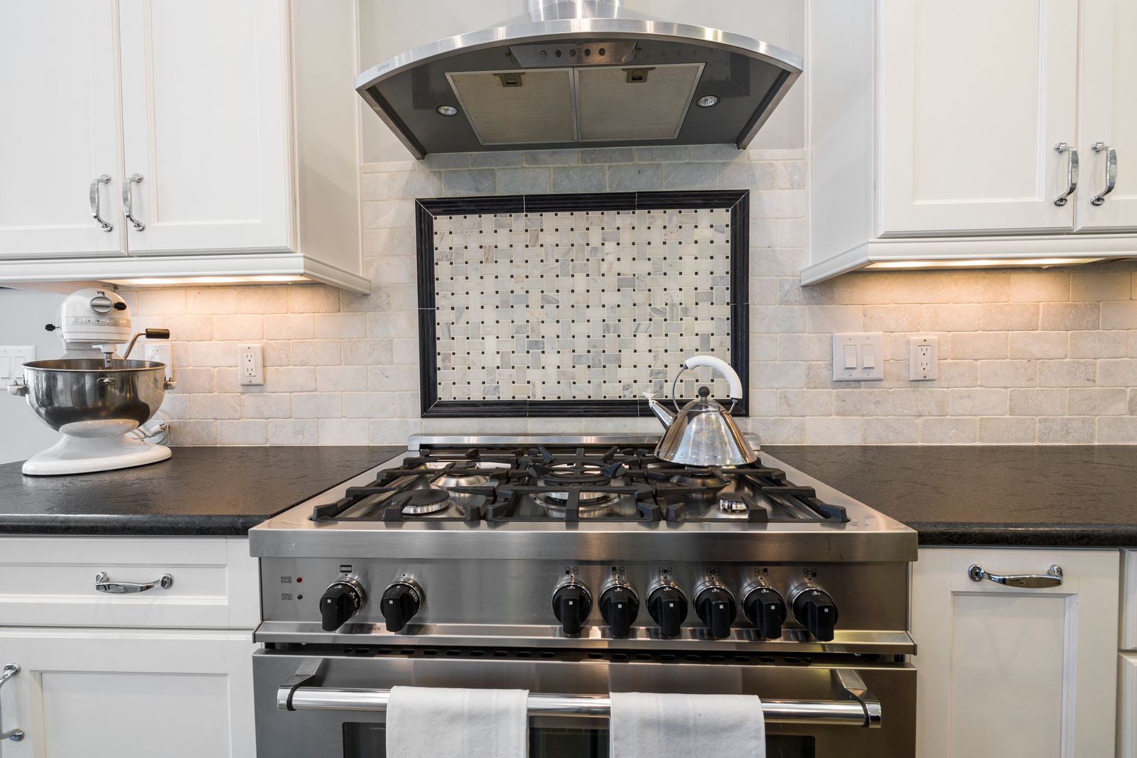 Stainless steel gas range with visible burner grates in a kitchen
