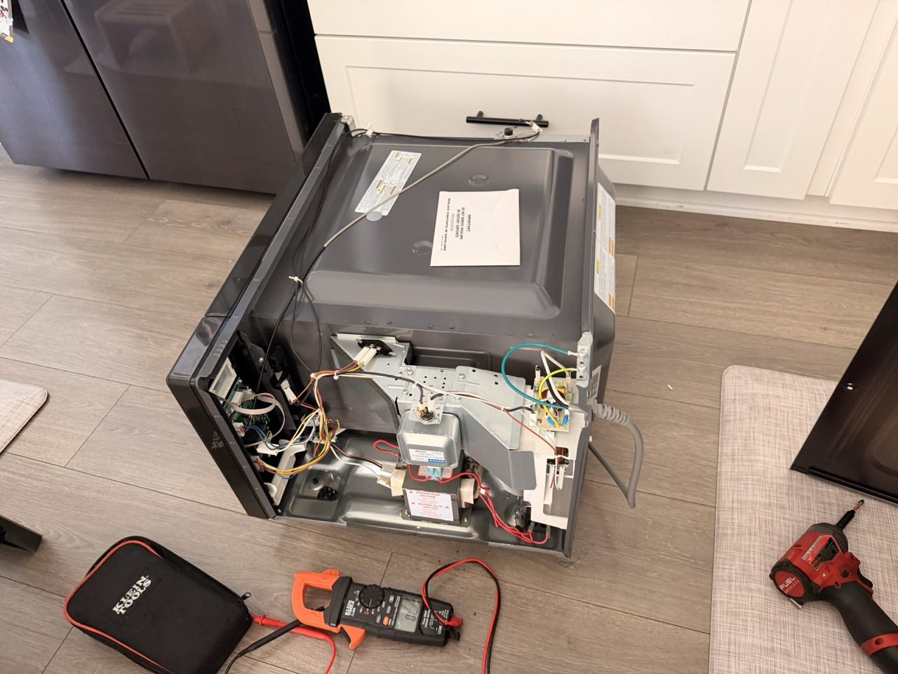 Era Service technician diagnosing a microwave with a multimeter during an appliance repair in the Inland Empire