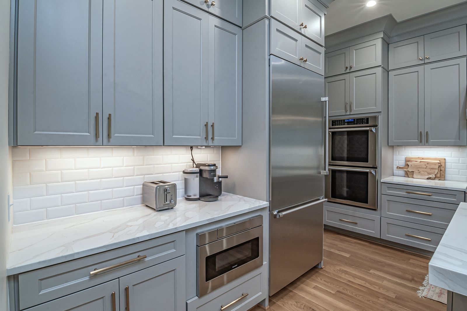 Built-in stainless refrigerator and freezer in a modern kitchen with white cabinetry