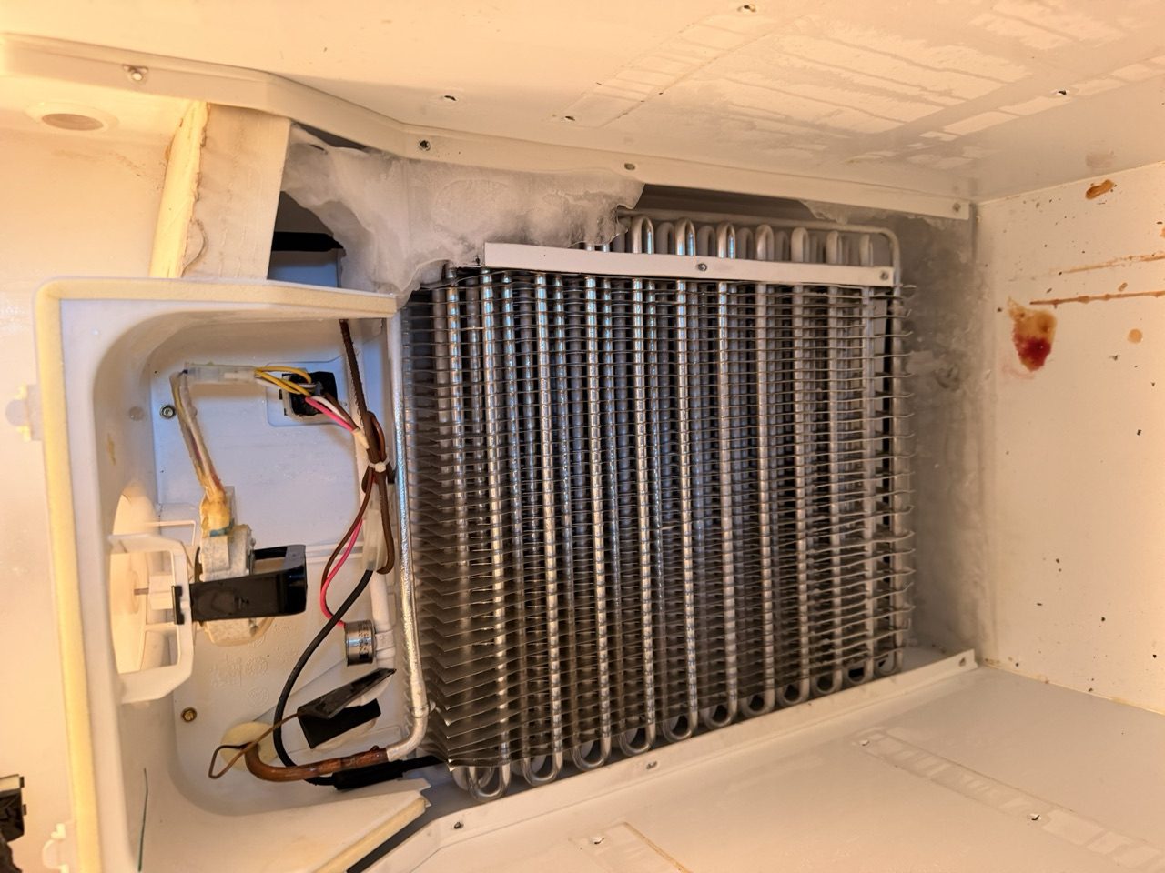 Era Service technician servicing the exposed evaporator coils of a refrigerator in the Inland Empire